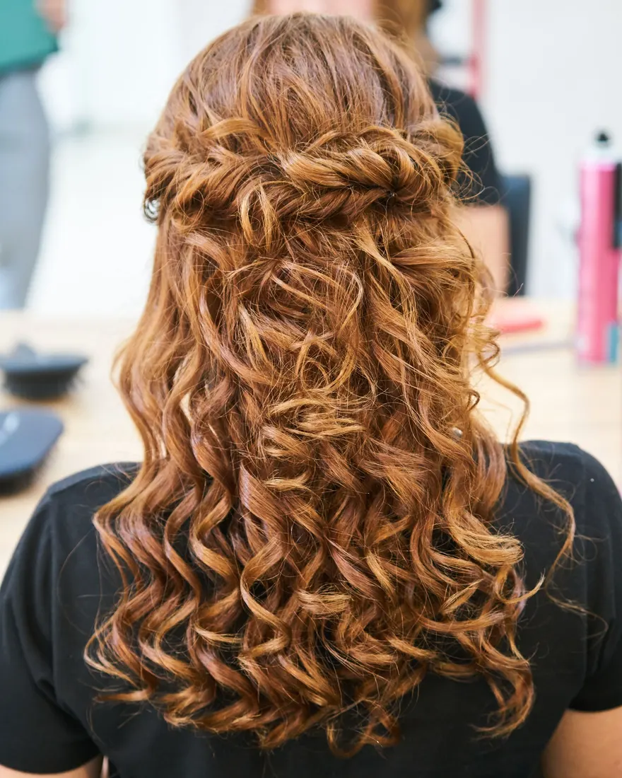 Halboffene Frisur mit gedrehten Strähnen und weichen Locken in warmem Kupferbraun, von hinten fotografiert